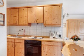 Uma cozinha com armários de madeira, lava-louças, forno, pia e cafeteira.