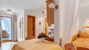 A bedroom with a bed, a wooden headboard, a bedside table with a lamp, a wooden cabinet, and a window with curtains.