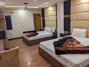 Habitación de hotel con dos camas, piso de madera, ventilador de techo y ventana.