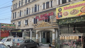 Ein Gebäude mit einem Schild für das Al Burraq Hotel, das traditionelle Architektur mit Säulen und dekorativen Elementen aufweist.