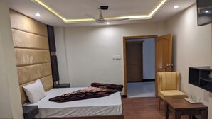 Ein modernes Hotelzimmer mit einem großen Bett, einem Nachttisch, einem Sessel und einem flachbildfernseher an der Wand.