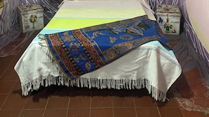 Ein Schlafzimmer mit einem Bett, einem gerahmten Bild an der Wand und einem gemusterten Teppich.