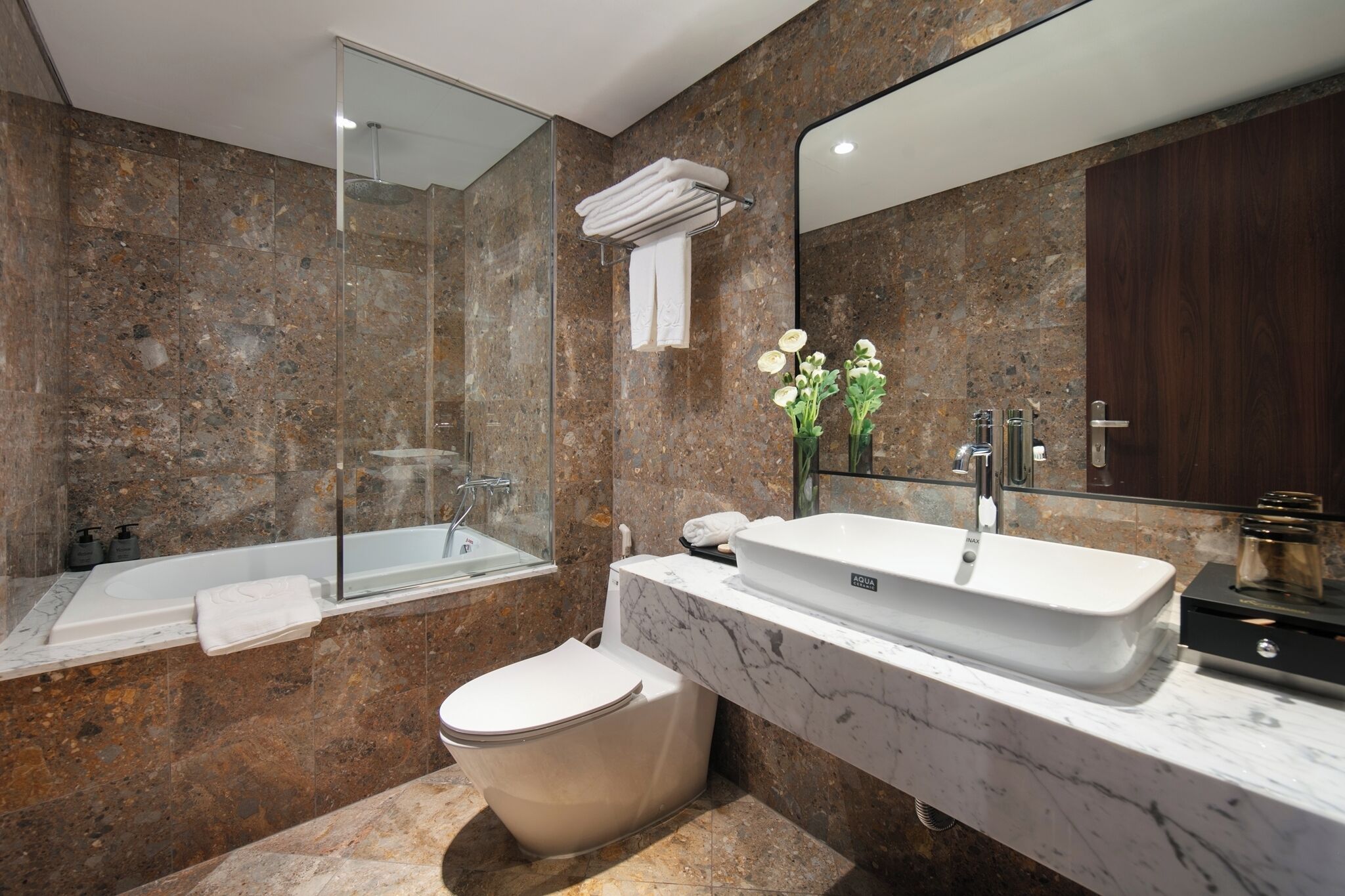A modern bathroom with a marble sink, a freestanding bathtub, and a glass-enclosed shower.