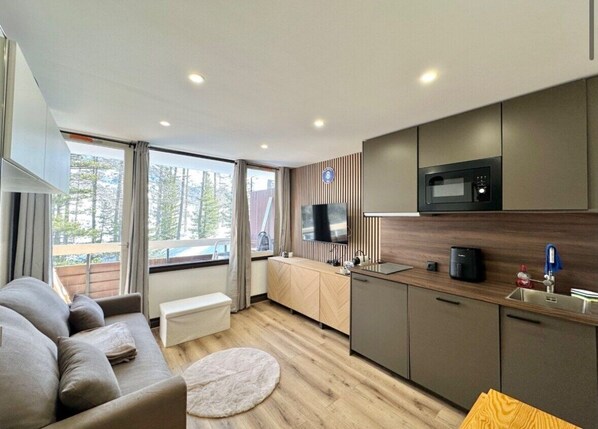 A modern kitchen with a microwave, sink, and wooden cabinets.