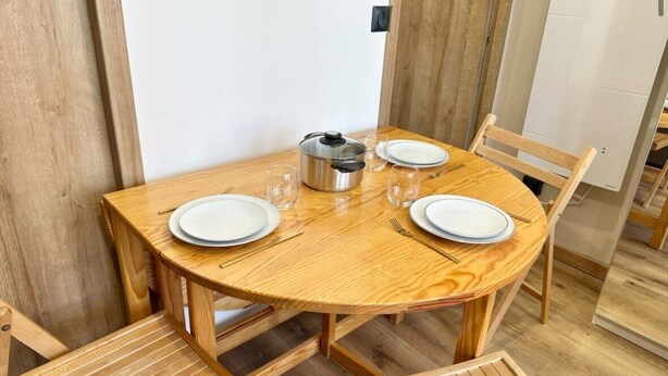Mesa de jantar de madeira com quatro cadeiras, um bule e copos.