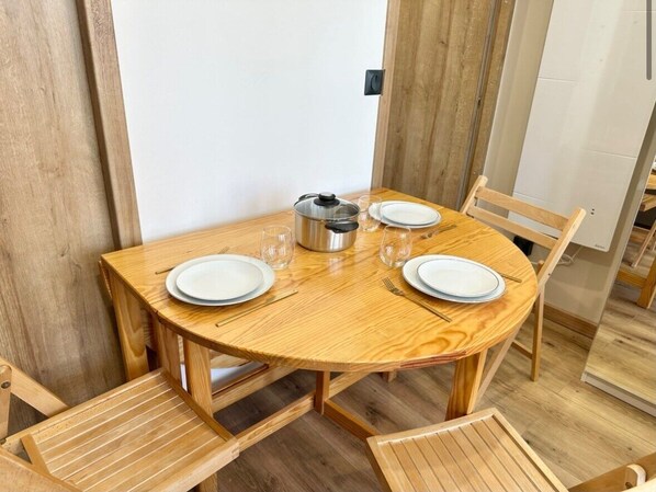 Una mesa de comedor de madera con cuatro sillas, una olla y cristalería.