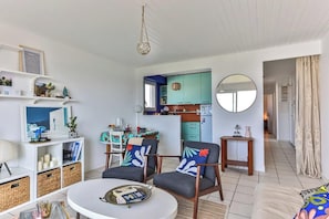 A compact living space with a dining area, kitchen, and a round mirror.