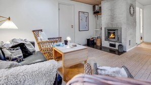 A cozy living room with a fireplace, a sofa, a chair, and a table.