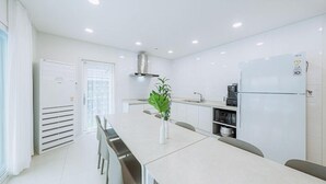 Una cucina moderna con mobili bianchi, una cappa in acciaio inossidabile, un forno a microonde integrato e un frigorifero.