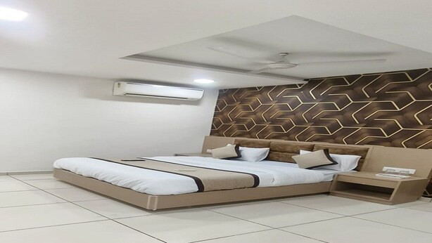 Een moderne slaapkamer met een groot bed, een nachtkastje, een wandairconditioner en een gestreept hoofdeinde.