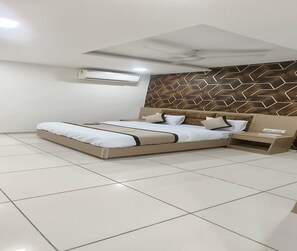 Un dormitorio moderno con una cama grande, una mesita de noche, aire acondicionado montado en la pared y un cabecero estampado.