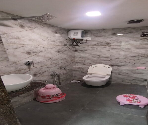 Un baño con lavamanos, inodoro, ducha y un taburete pequeño rosa.