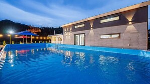 A modern building with a swimming pool, large windows, and a mountain backdrop. - jayeonsog gong gan (Gapyeong)