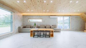 A spacious living area with a wooden ceiling, a large window, a sofa set, and a dining table with chairs. - jayeonsog gong gan (Gapyeong)