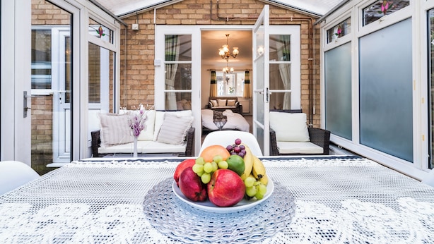 A dining area with a table set for a meal, a fruit bowl, and a cozy seating area with a sofa and chairs.