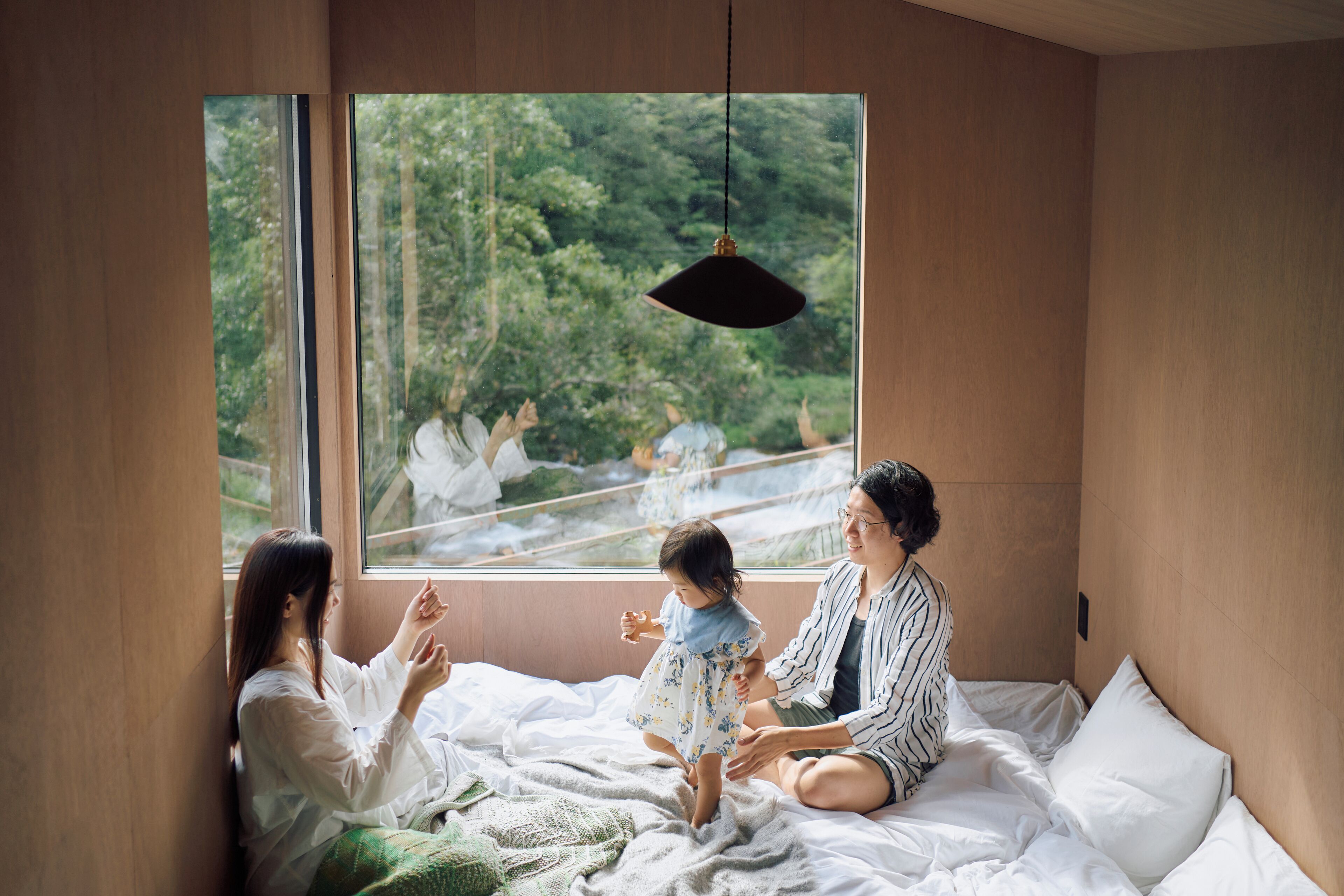 Una habitación con un ventanal grande, una cama y una lámpara colgante.