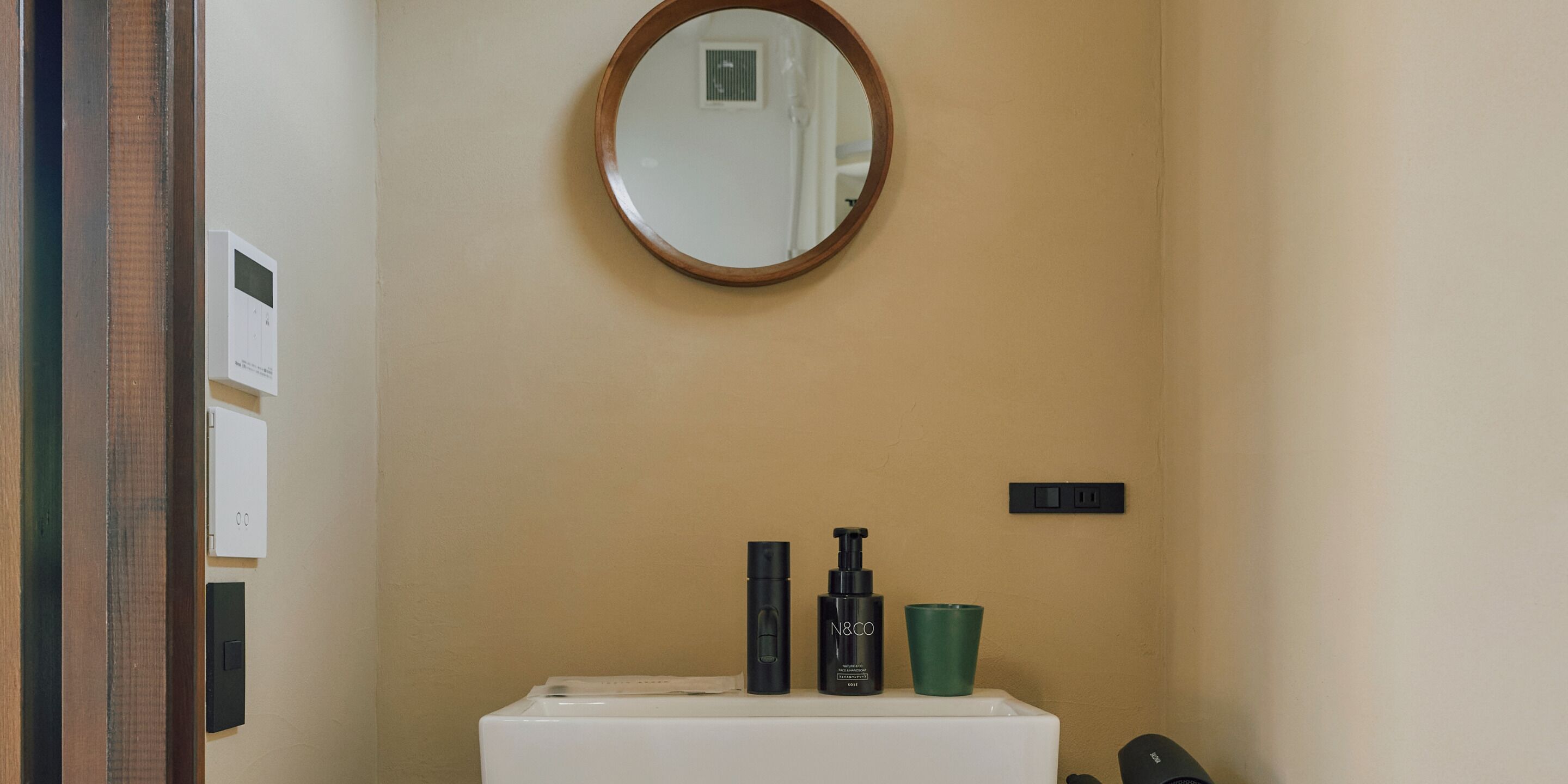 Ein Badezimmer mit einem weißen Waschbecken, einem Spiegel und Toilettenartikeln auf der Ablagefläche.