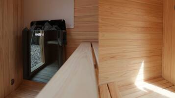 Un sauna con banco, calentador en la pared y suelo de madera.