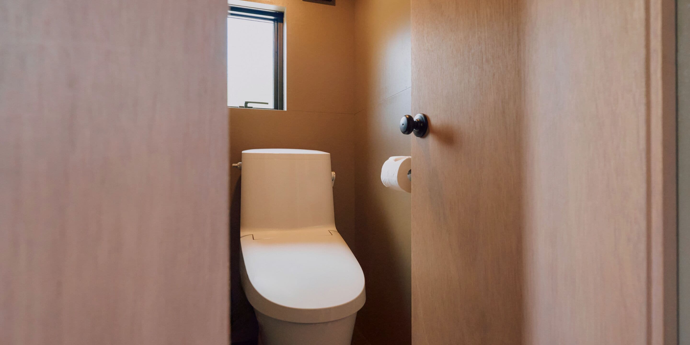 A small, compact bathroom with a toilet, a window, and a door.