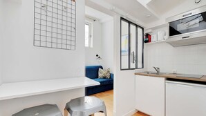 Una cucina compatta con un piano di lavoro bianco, un forno integrato e un lavello.
