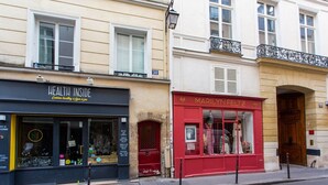 Una vista di strada con un negozio di prodotti naturali chiamato 'Health Inside' e una boutique chiamata 'Marilyn Feltz'.