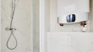 Un bagno con doccia, un termoconvettore a parete e un pannello di controllo.