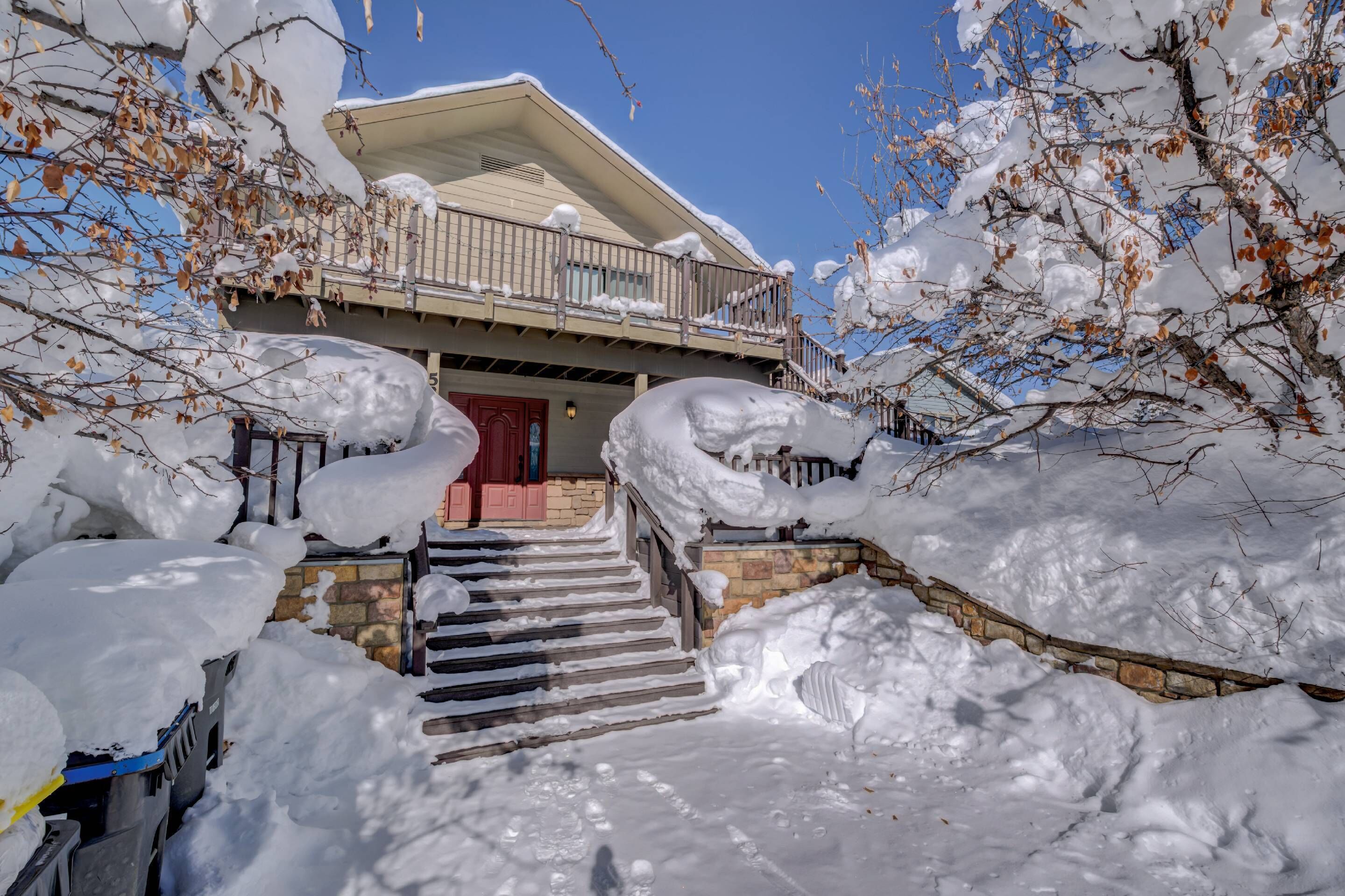 Un bâtiment à deux étages, dont l’entrée et les marches sont recouvertes de neige et qui mène à une porte rouge.