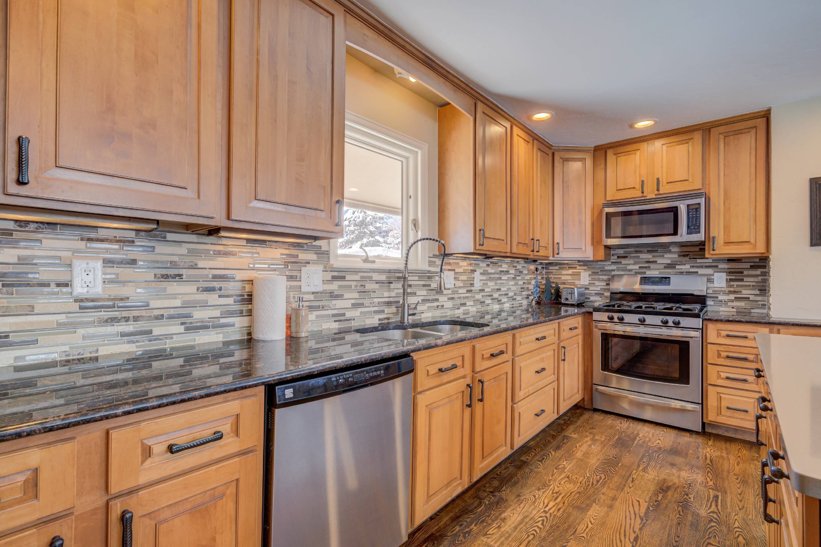 A modern kitchen with wooden cabinets, a stainless steel dishwasher, a built-in microwave, and a large oven.