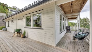 Une maison dotée d’un porche abrité, d’une terrasse en bois et de meubles d’extérieur.