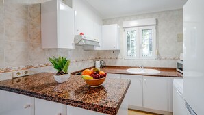 A modern kitchen with granite countertops, white cabinets, a built-in sink, and a window providing natural light. - Vacation home Verena by Interhome (Dénia)