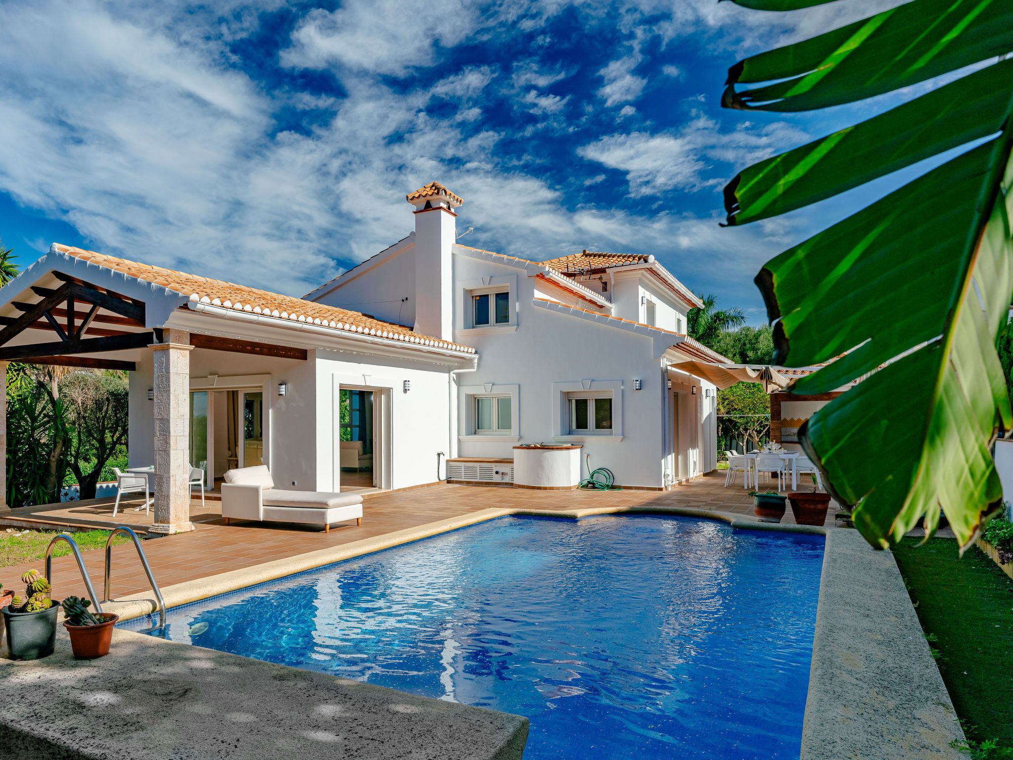 Une maison moderne dotée d’une piscine, d’un patio couvert et d’un jardin.