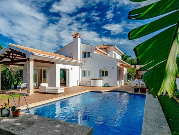 A modern house with a swimming pool, a covered patio, and a garden.