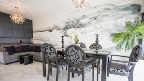 A dining area with a marble wall, a sofa, and a chandelier. - Chic Condo with Gym & Private Roof (Mexico City)
