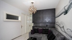 A modern living room with a grey sofa, black and purple cushions, a black side table, and a decorative wall panel. - Chic Condo with Gym & Private Roof (Mexico City)