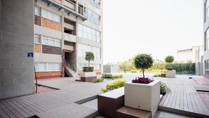 A courtyard with a concrete staircase, a small tree, and a planter with red flowers. - Chic Condo with Gym & Private Roof (Mexico City)