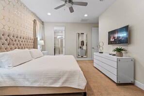 Experience relaxation in this stylish bedroom featuring a plush tufted headboard and soft neutral tones. The spacious layout includes a sleek dresser and a mounted TV, creating an ideal spot to unwind after a day of adventure.