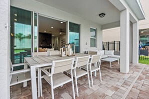 Step outside to a lovely patio with a spacious white dining table and comfy chairs, perfect for al fresco meals. Large sliding doors enhance the natural light and connect the vibrant indoor space with the outdoors.
