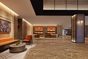 Un vestíbulo moderno con mostrador de recepción, zona de estar e iluminación decorativa.