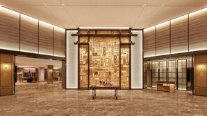 Un hall d’entrée spacieux, agrémenté d’un mur aux motifs traditionnels, d’un comptoir de réception et d’un espace détente avec des sièges.