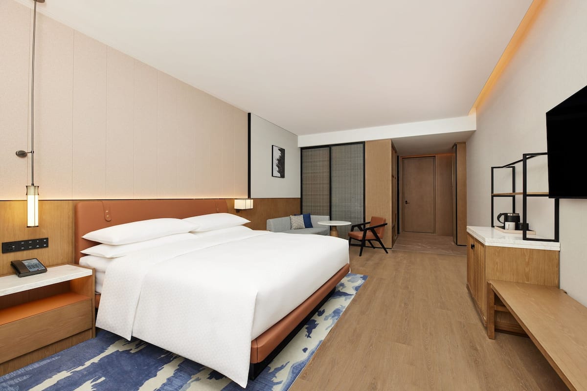 Ein modernes Hotelzimmer mit einem großen Bett, einem Nachttisch und einem Schreibtisch mit Stuhl.