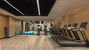Une salle de sport équipée de tapis de course, de ballons d'exercice et d'appareils de musculation.