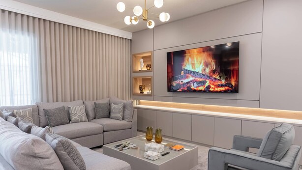 A modern living room with a sectional sofa, a coffee table, and a flat-screen TV mounted on the wall. - 10BR house sleeps 22 with game room (Clermont)