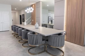 Uma cozinha moderna com uma bancada comprida, banquetes cinzas e um candelabro.