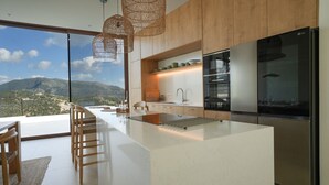 A modern kitchen with a large island, stainless steel appliances, and a view of the mountains. - Villa Mulberry in Vasiliki (Lefkada)