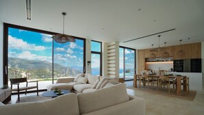 A modern living room with a large sofa and a dining area with wooden furniture. - Villa Mulberry in Vasiliki (Lefkada)