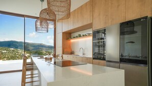A modern kitchen with a large island, wooden cabinets, and a view of the mountains. - Villa Mulberry in Vasiliki (Lefkada)