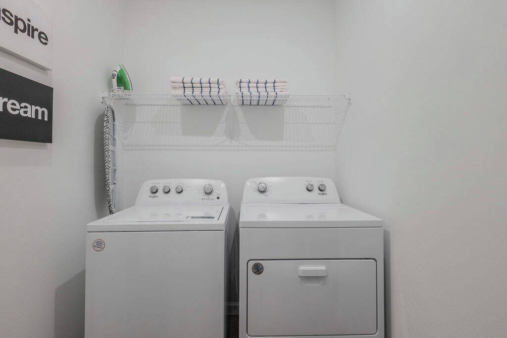 A laundry area with two white washing machines and a drying rack with folded clothes.