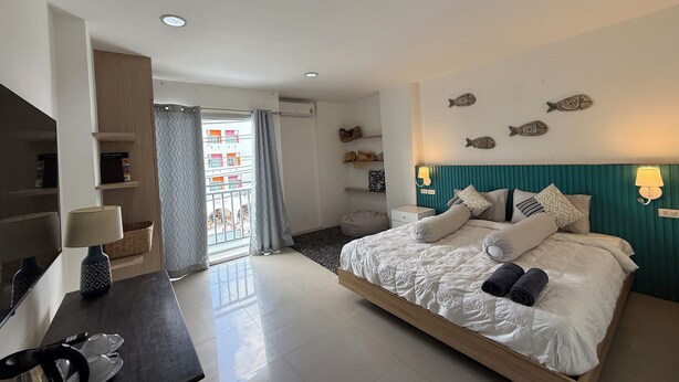 A modern bedroom with a bed, bedside tables, a desk, and a view of the outside.