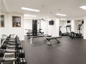 Un gimnasio con equipo de ejercicio, una banca y mancuernas.