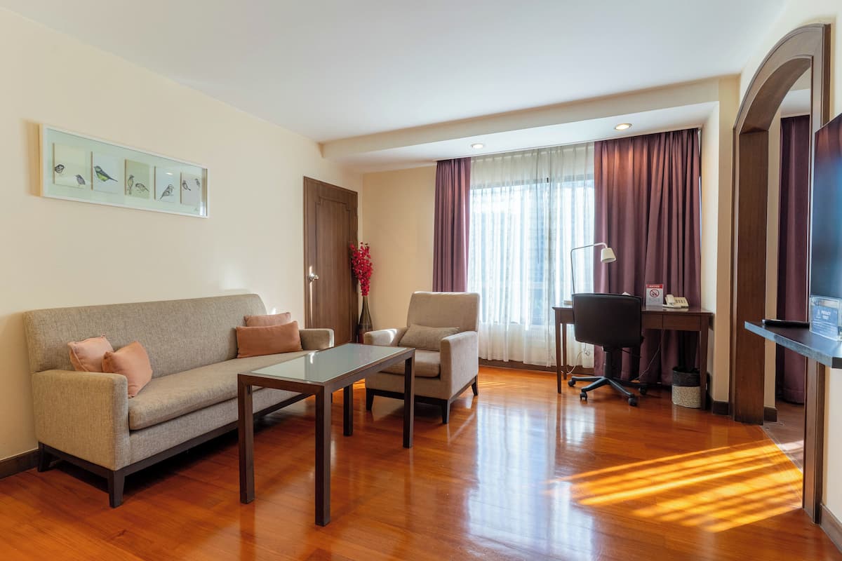 Una sala de estar moderna con sofá, sillones, una mesa de centro y un escritorio con computadora.